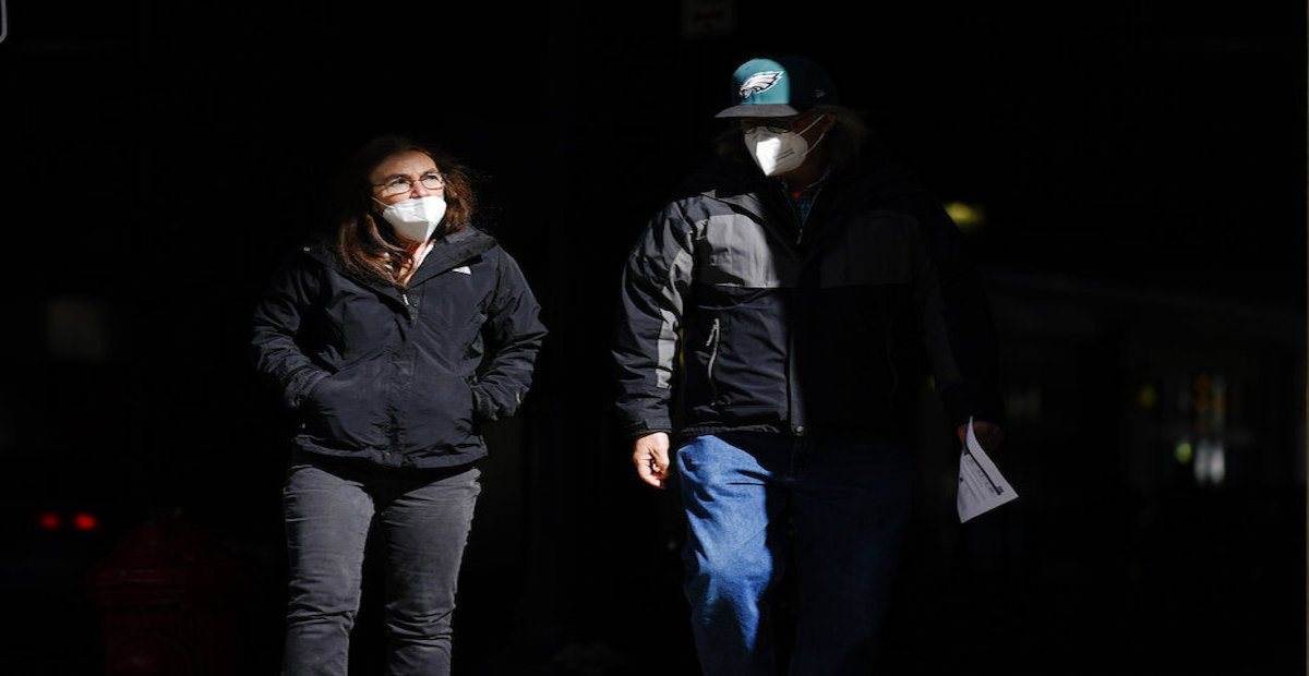 People wearing face masks as a precaution against the coronavirus walk in Philadelphia on March 3, 2021.