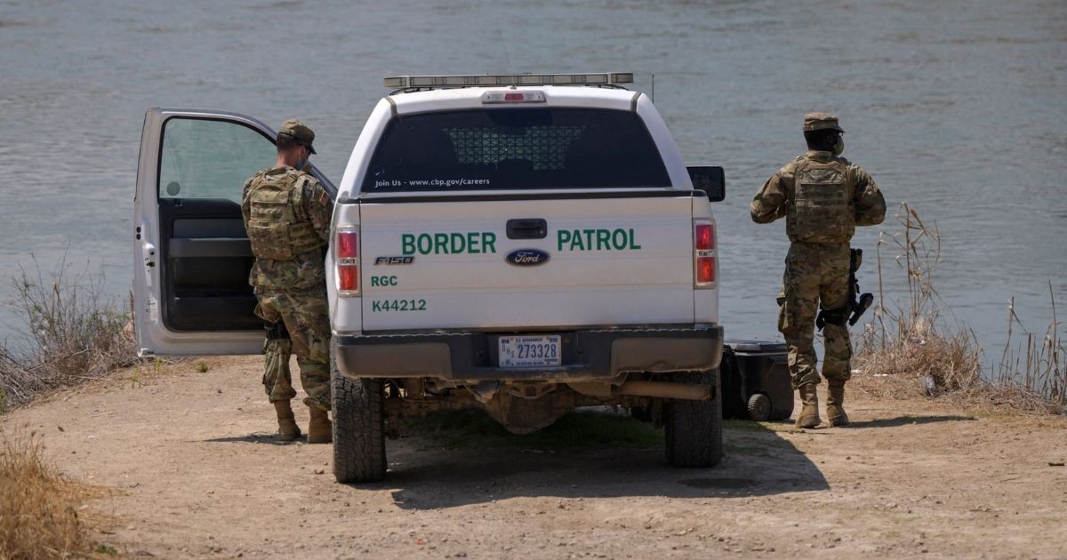 Border Patrol agents stand before the Rio Grande river and a suburb of the Mexican city of Ciudad Miguel Aleman, in the southern Texas border city of Roma, on March 27, 2021.