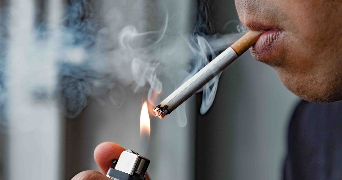 A person is pictured lighting a cigarette in the stock image above.