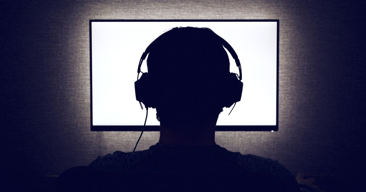 A man wearing headphones is pictured sitting in front of a computer monitor in the stock image above.