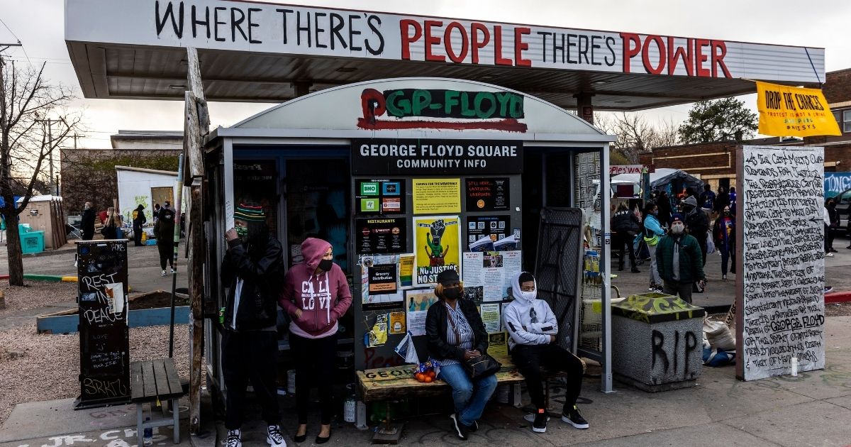 People sit at a bus stop at George Floyd Square in Minneapolis on Wednesday.
