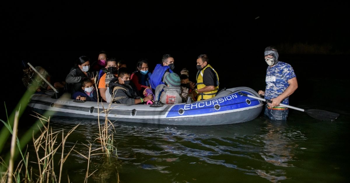 A "coyote" people smuggler, right, guides an inflatable boat carrying migrants from Central America arriving illegally from Mexico to the U.S. on the Rio Grande river at the border city of Roma on March 29, 2021.