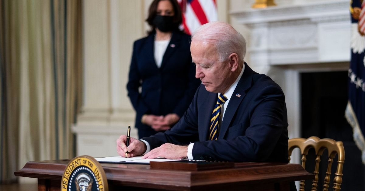 President Joe Biden signs an executive order on the economy with Vice President Kamala Harris on Feb. 24, 2021, in the State Dining Room of the White House in Washington, D.C.