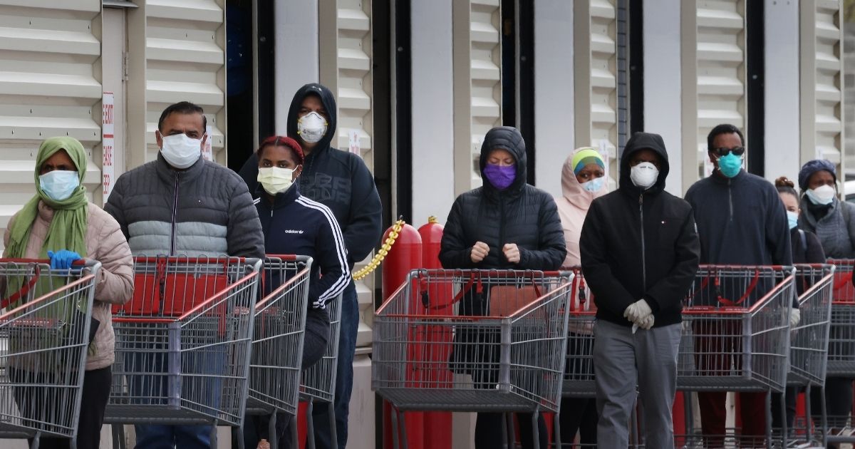 Customers wear face masks as they line up to enter a Costco Wholesale store on April 16, 2020, in Wheaton, Maryland.