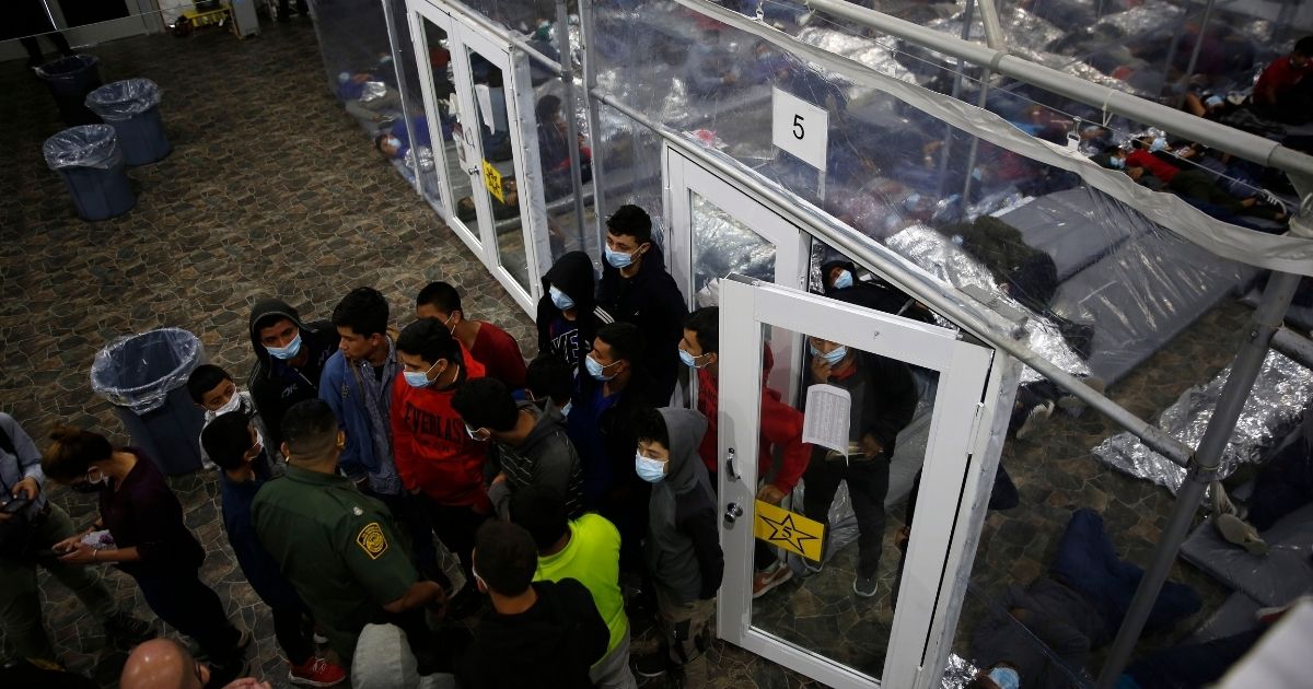 Minors talk to an agent outside a pod at the Department of Homeland Security holding facility run by the Customs and Border Patrol (CBP) on March 30, 2021, in Donna, Texas.