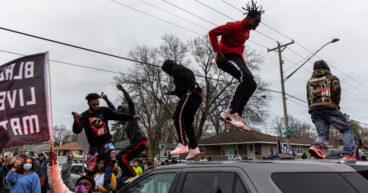 Rioters jump on top of a police car Sunday during demonstrations that broke out after an officer shot and killed Daunte Wright in Brooklyn Center, Minnesota.