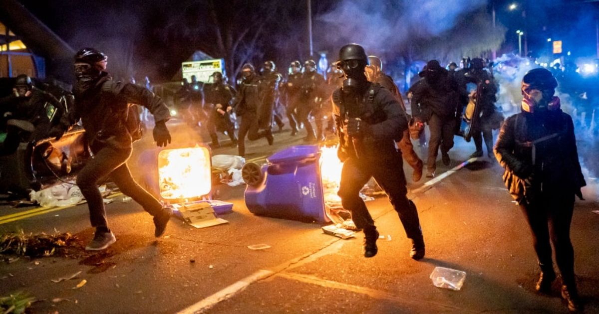 Portland police officers chase rioters on April 12, 2021, in Portland, Oregon.