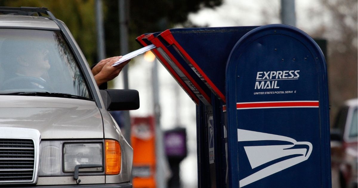 A postal customer drops letters into a mailbox in San Francisco.
