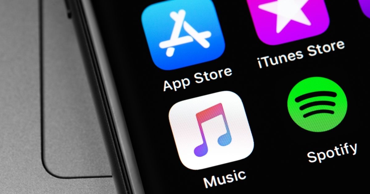 Icons for the Spotify and Apple Music apps are seen on an iPhone screen.