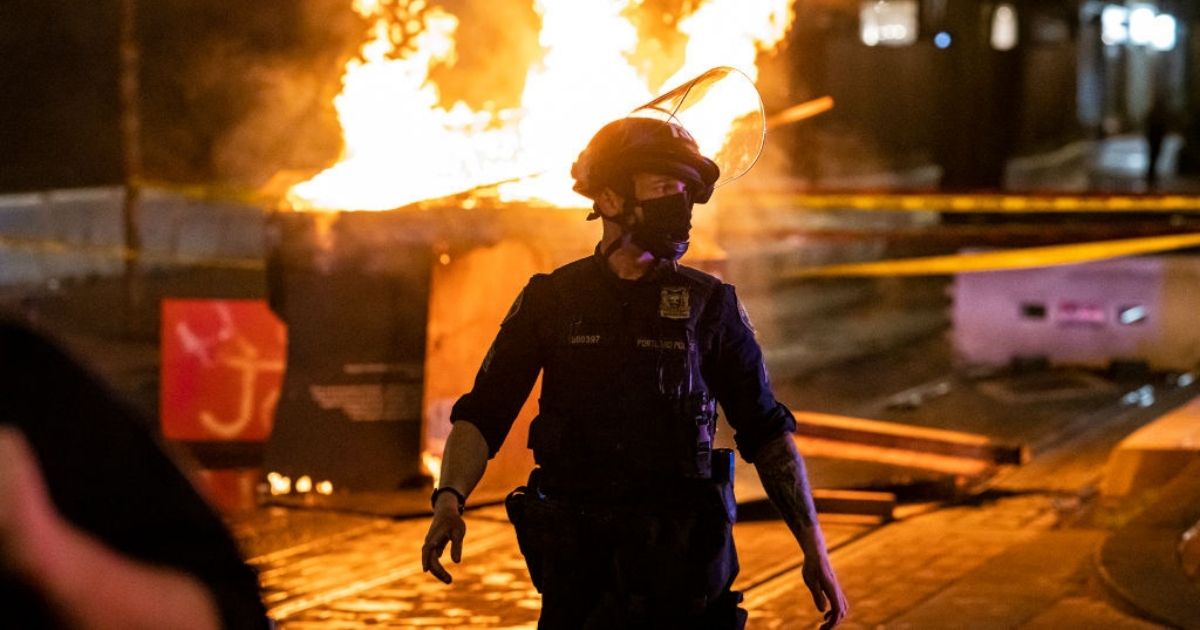 A Portland police officer responds to a fire set by rioters following a police shooting on Saturday in Portland, Oregon.