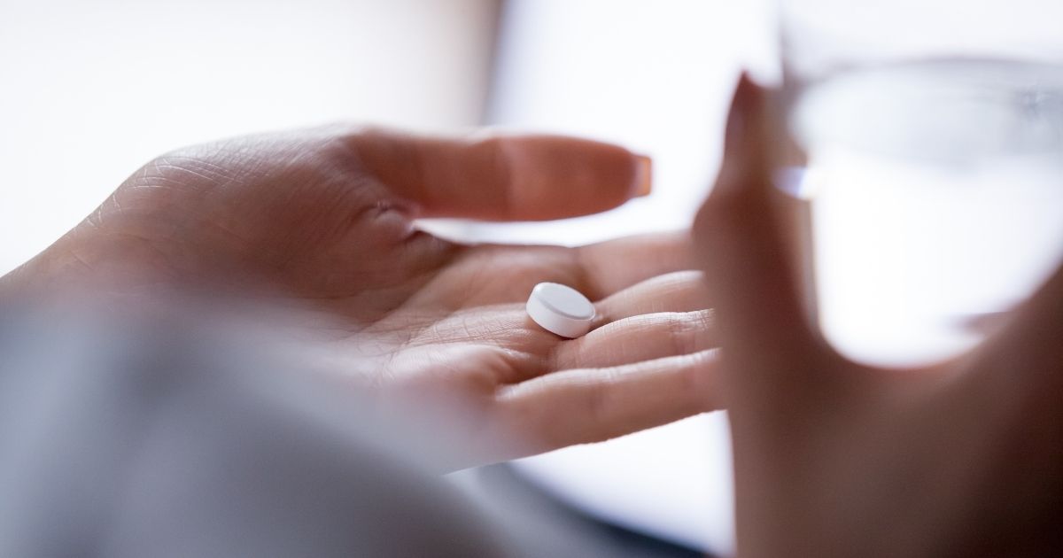 A woman holds a pill in this stock image.
