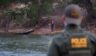 A Border Patrol agent stands opposite a man believed to be a "coyote" on the banks of the Mexican side of the Rio Grande river in the U.S. border city of Roma on Mach 27, 2021.