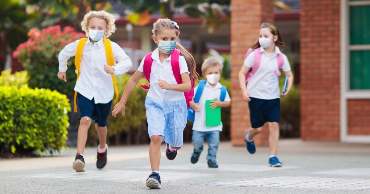 Schoolchildren are pictured wearing masks outside in the stock image above.