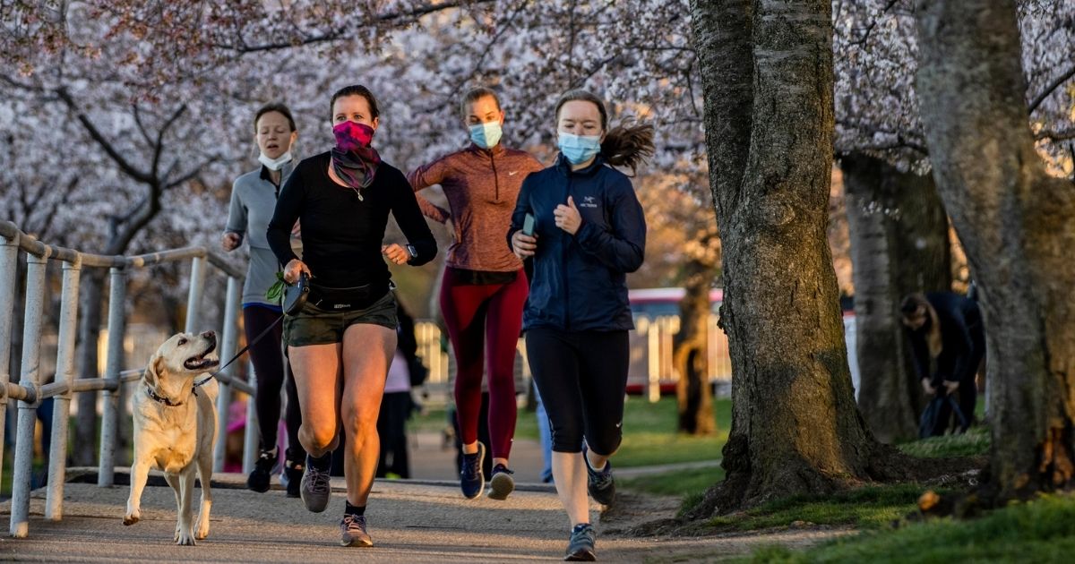 People wearing masks run among the Japanese Cherry Blossom trees along the Tidal Basin in Washington on March 27.