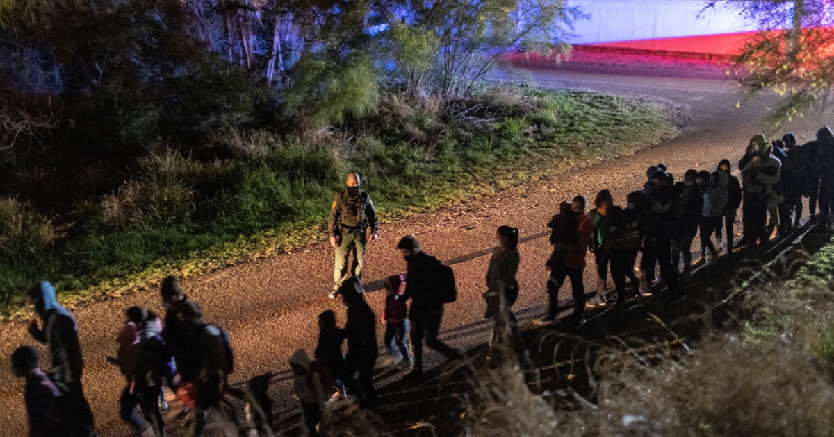 In a nighttime scene, a U.S. Border Patrol agent watches a line of illegal immigrants who crossed the Rio Grande River near Roma, Texas, on Friday.