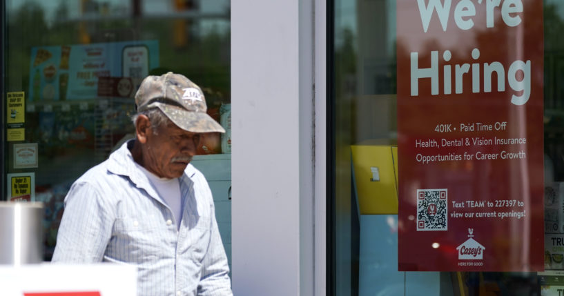 A customer walks past a hiring sign at a gas station in Buffalo Grove, Ill., June 9. More Americans applied for unemployment benefits last week, the fifth consecutive week that claims topped the 230,000 mark, the Labor Department reported.