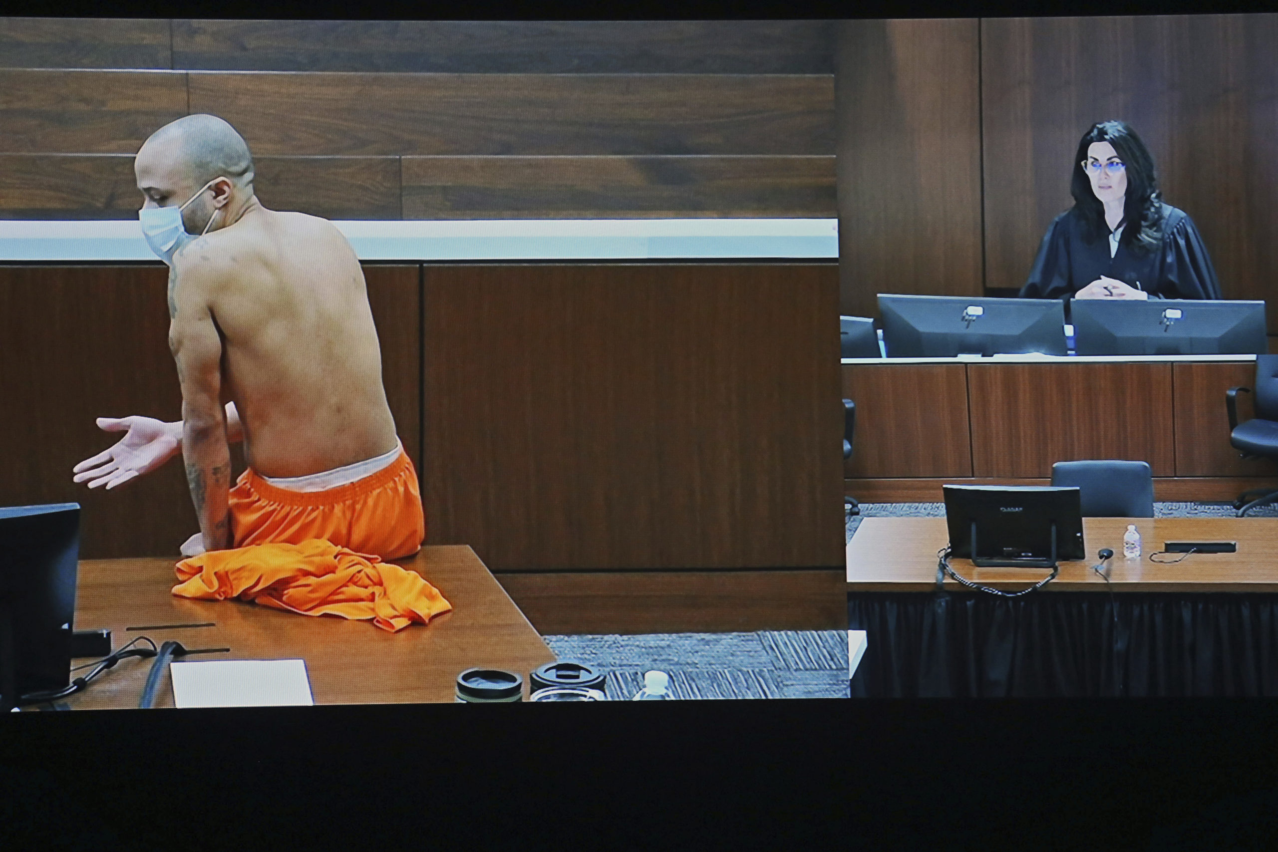 Darrell Brooks sits shirtless in an empty court room after being removed from the first day of his trial for continuously interrupting Waukesha County Circuit Judge Jennifer Dorow, on screen to the right. Brooks is accused of killing six people and injuring dozens more when he allegedly drove his SUV through a Christmas parade in Wisconsin last year.