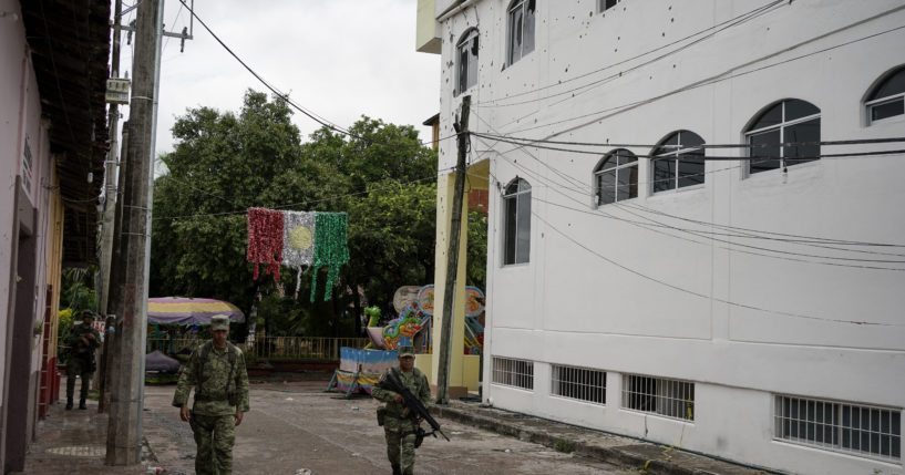 Soldiers walk past City Hall in San Miguel Totolapan, Mexico, which is riddled with bullet holes after 20 people were killed in an attack on Wednesday.