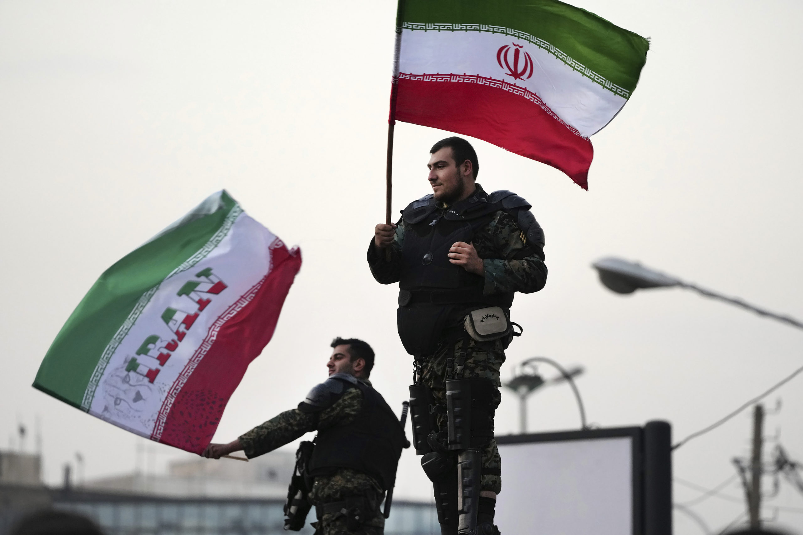 Two anti-riot police officers wave Iranian flags during a street celebration after Iran defeated Wales in the World Cup on Friday.