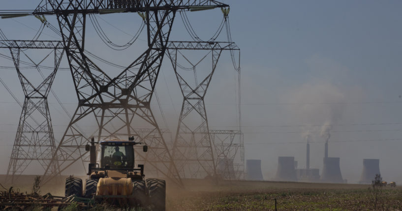 A farmer plows land underneath electrical pylons connected to the coal-powered electricity generating plant near Johannesburg, South Africa, on Thursday.