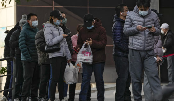 Beijing residents wait in line to enter a store on Sunday.