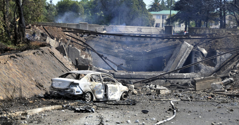 A burned-out vehicle marks the spot where a gas tanker exploded under a bridge in Boksburg, east of Johannesburg, South Africa, Saturday. A truck carrying liquified petroleum gas exploded, killing at least 8 people and injuring more than 50 others.