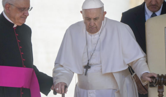 Pope Francis is helped by his aide Monsignor Leonardo Sapienza, left, as he walks with a cane to his weekly general audience in St. Peter's Square at The Vatican, on June 1.