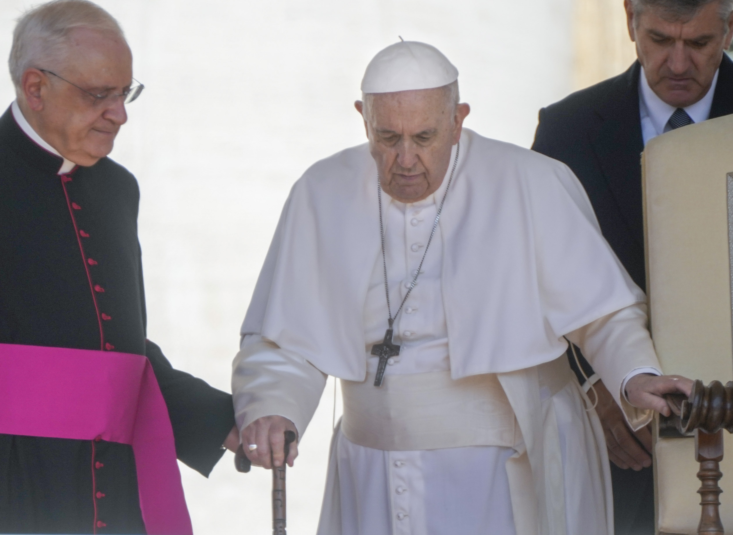 Pope Francis is helped by his aide Monsignor Leonardo Sapienza, left, as he walks with a cane to his weekly general audience in St. Peter's Square at The Vatican, on June 1.