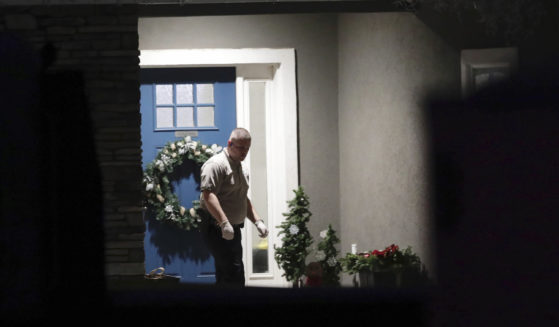 A law enforcement official stands near the front door of the Enoch, Utah, home where eight family members were found dead from gunshot wounds on Wednesday.