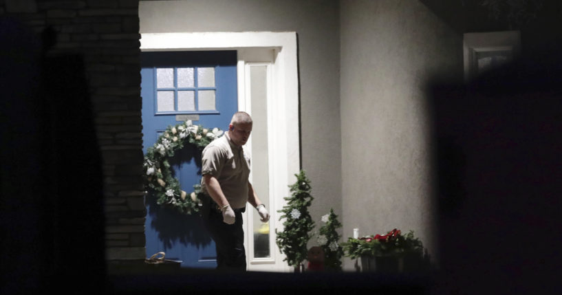 A law enforcement official stands near the front door of the Enoch, Utah, home where eight family members were found dead from gunshot wounds on Wednesday.