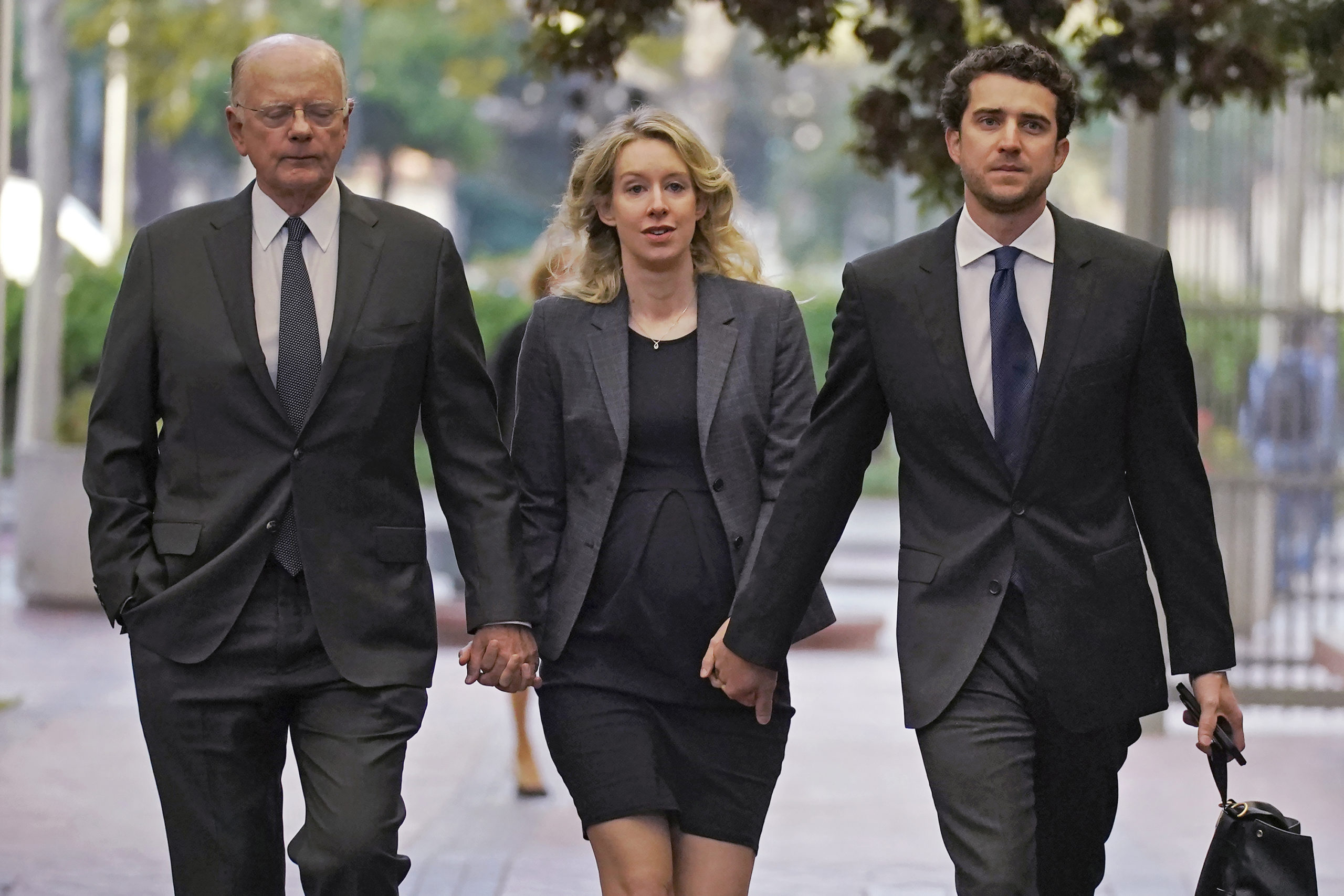 Former Theranos CEO Elizabeth Holmes arrives at federal court in San Jose, California, on Oct. 17 with her father, Christian Holmes IV, left, and her partner, Billy Evans.