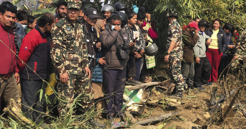 Locals of Pokhara, Nepal, gather to look at the wreckage of a regional plane that crashed on Sunday.