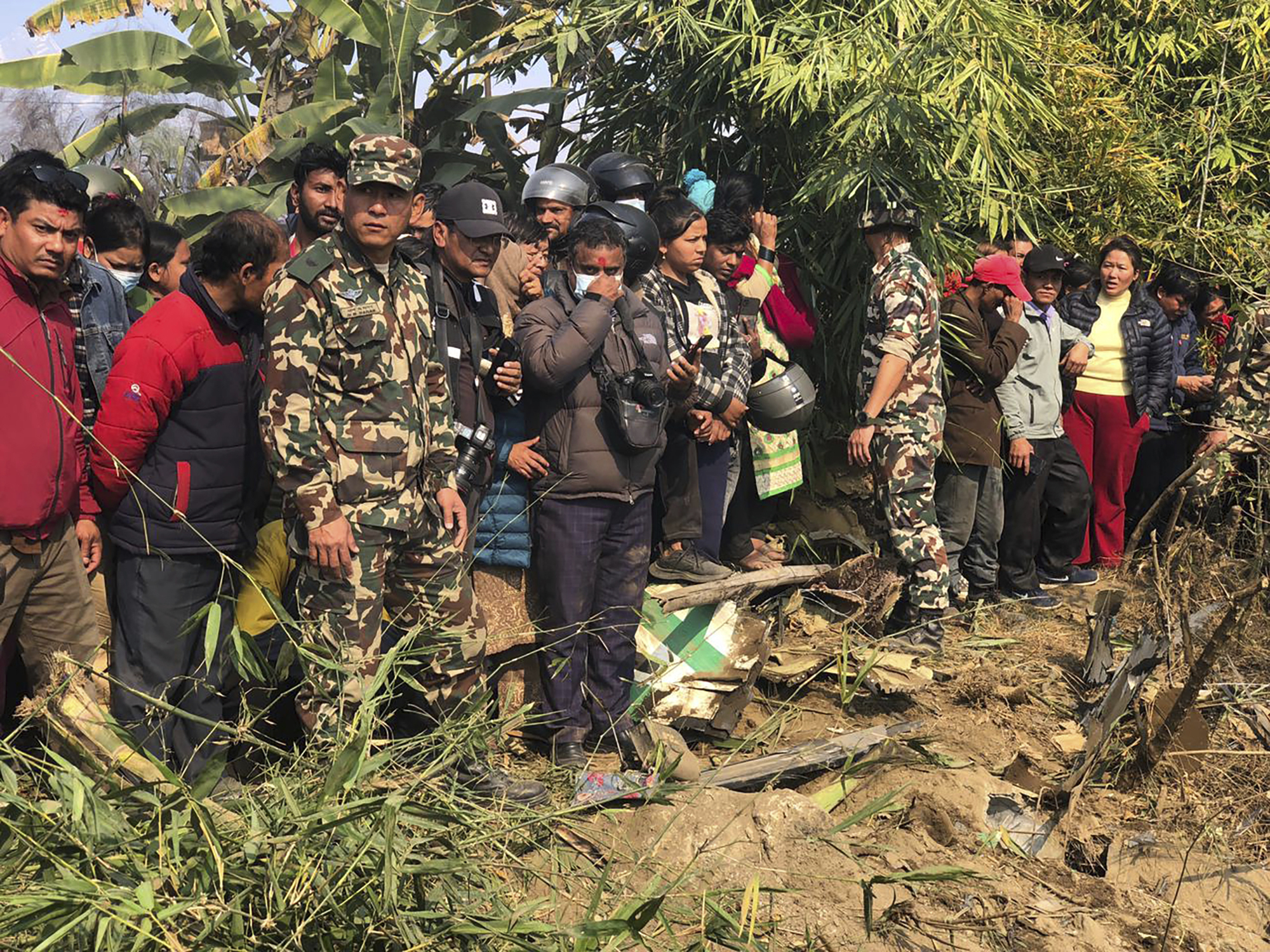 Locals of Pokhara, Nepal, gather to look at the wreckage of a regional plane that crashed on Sunday.