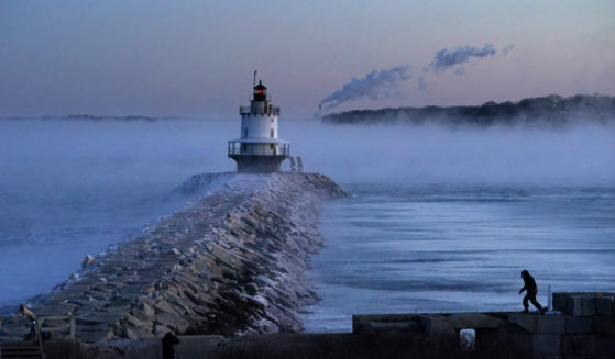 A man walks on a sea wall near Spring Point Ledge Light in South Portland, Maine, on Saturday. Morning temperatures there hovered near 10 below zero.