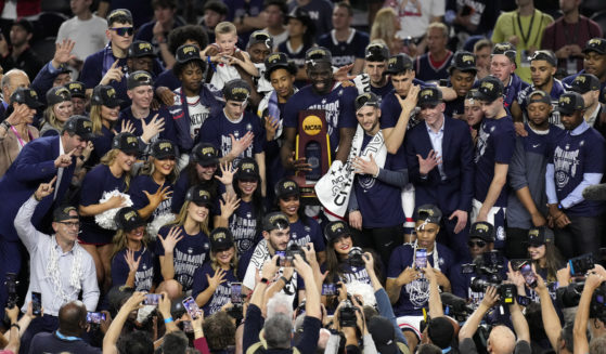 Players for UConn pose with coaches after winning the NCAA Tournament over San Diego State in Houston, Texas, on Monday night.