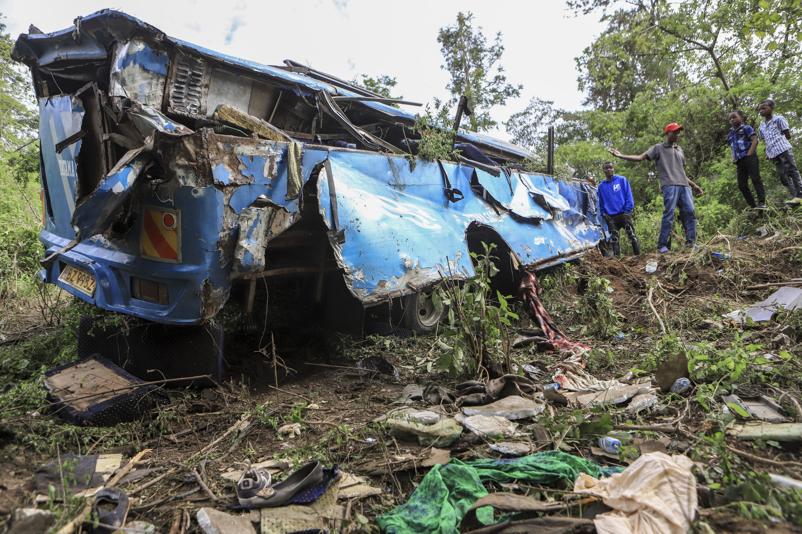 People observe the wreckage at the scene of a bus crash involving dozens of mourners who were returning from a funeral, near Mwatate, Kenya, on Saturday.