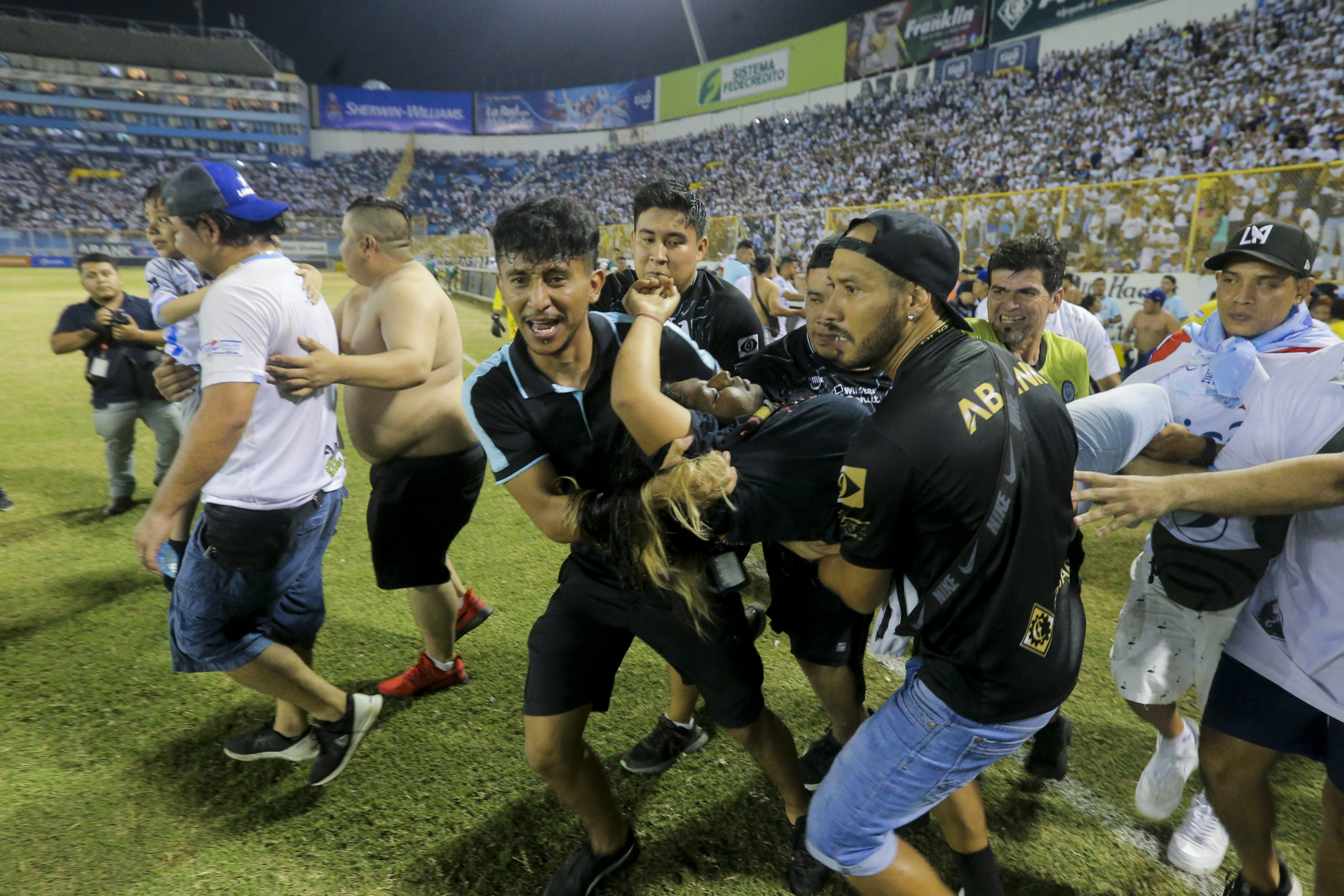 An injured fan, center, is carried on the field at the soccer stadium in San Salvador, El Salvador, after a stampede broke out during a soccer game on Saturday.