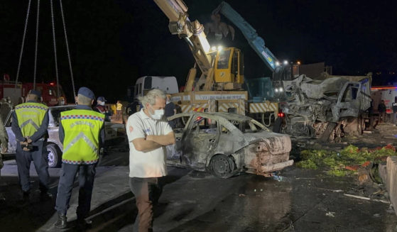 Turkish police officers and emergency personnel work next to burned vehicles after a crash late Saturday on the Iskenderun-Antakya highway in south Turkey.