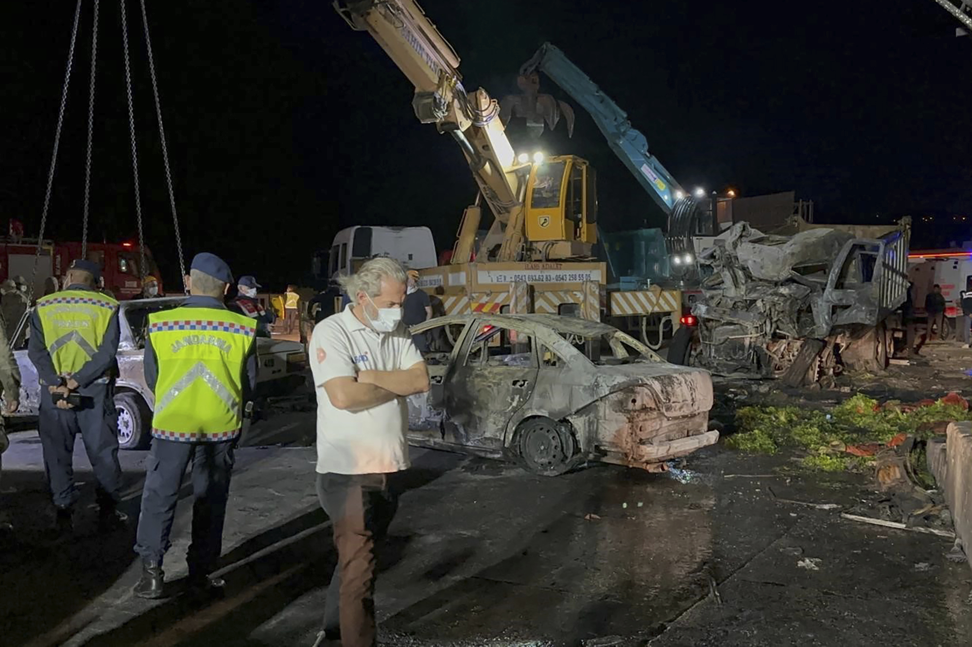 Turkish police officers and emergency personnel work next to burned vehicles after a crash late Saturday on the Iskenderun-Antakya highway in south Turkey.