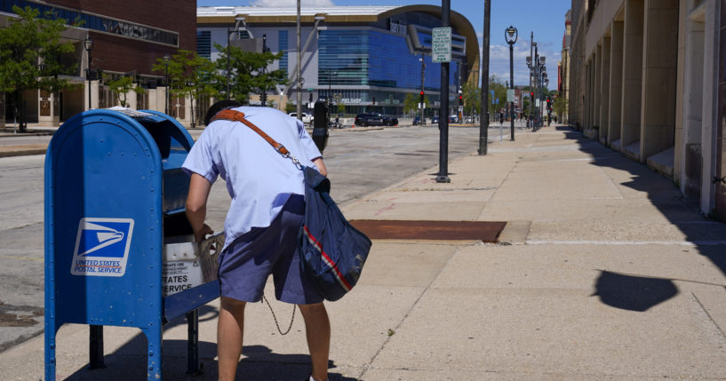 A postal worker emptying a mailbox