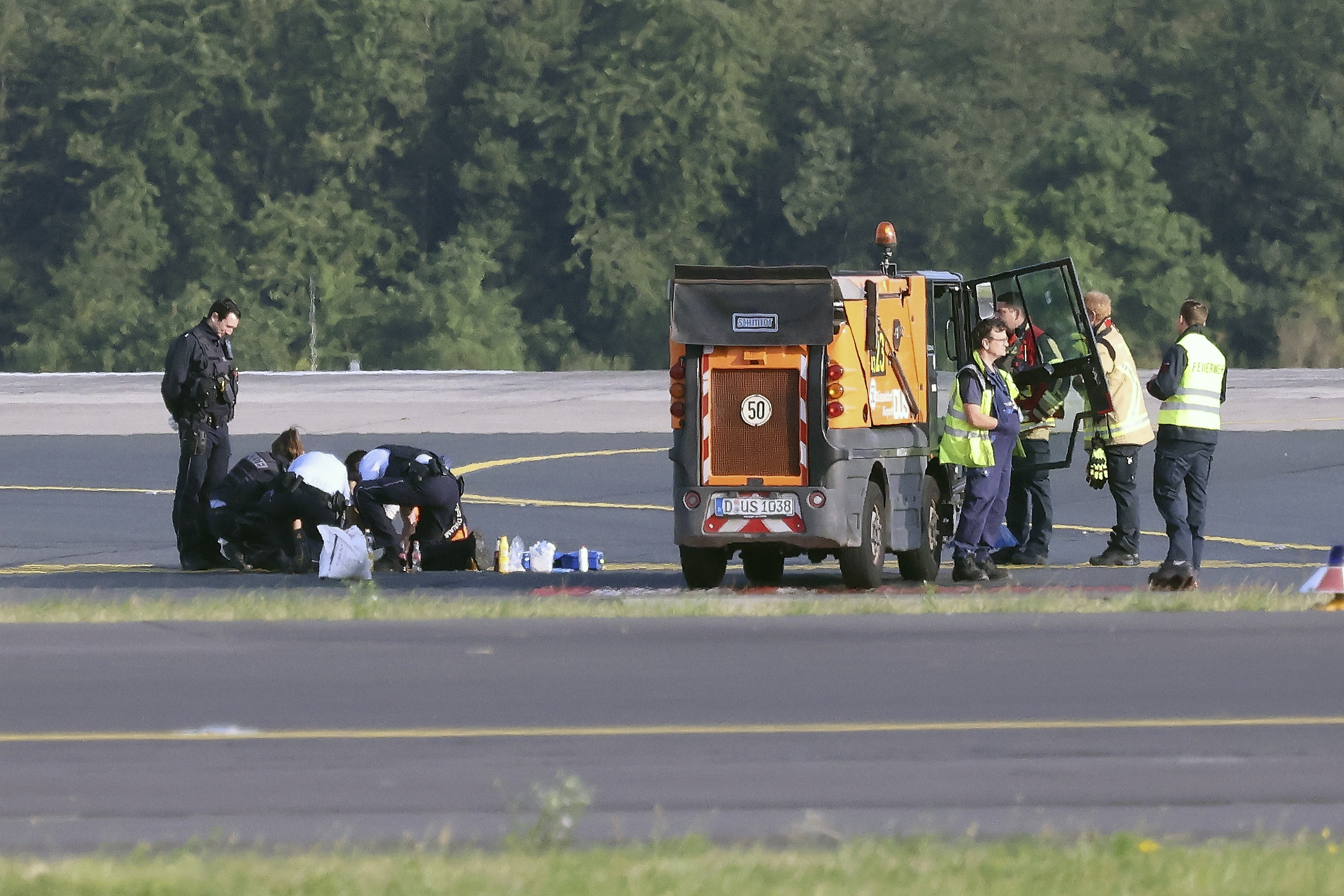 Police officers and security personnel stand on the airfield in Dusseldorf, Germany, on Thursday and try to detach activists of the group Last Generation who glued themselves to the asphalt.