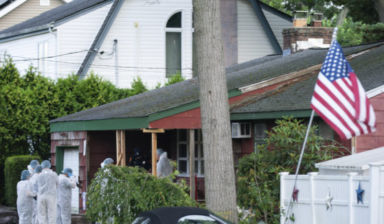 Crime laboratory officers arrive Friday at the house where a suspect was taken into custody on New York's Long Island in connection with a long-unsolved string of killings known as the Gilgo Beach murders.