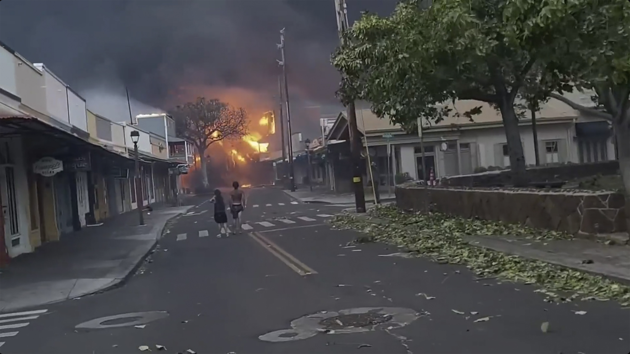 People walk the streets of Lahaina town, Hawaii, on Wednesday as wildfires engulf multiple structures, forcing residents to evacuate.