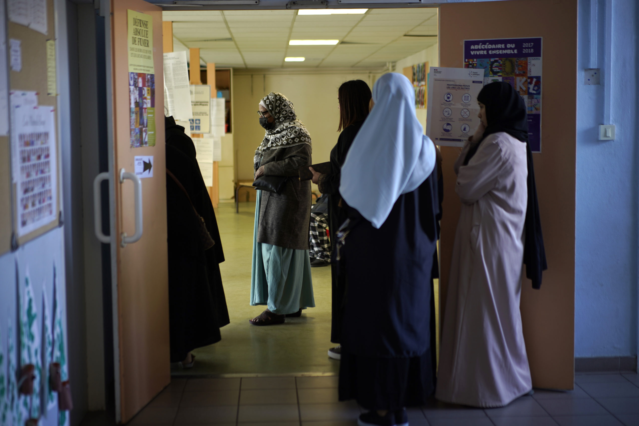 Women wait in line before voting for the first round of the presidential election at a polling station Sunday, April 10, 2022 in the Malpasse northern district of Marseille, southern France.