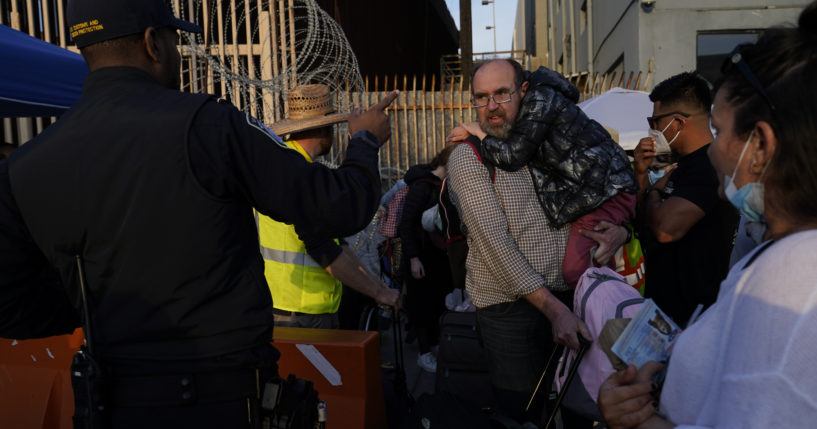 Ukrainian refugees speak with a U.S. Customs and Border Protection official as the refugees prepare to cross the border on April 4, 2022, in Tijuana, Mexico.