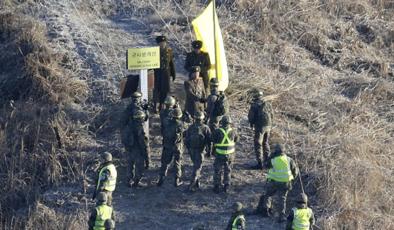 A South Korean army solider, center bottom, shakes hands with a North Korean army soldier, center top, before crossing the Military Demarcation Line inside the Demilitarized Zone to inspect a dismantled North Korean guard post in the central section of the inter-Korean border in Cheorwon on Dec. 12, 2018.