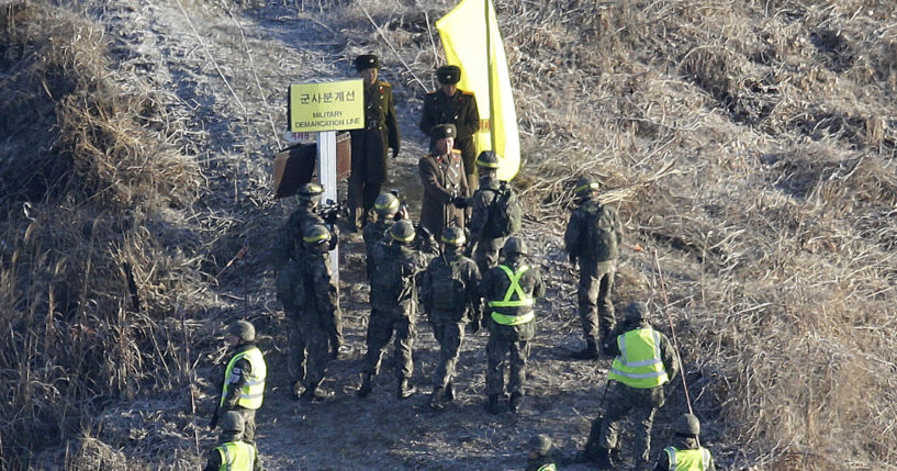 A South Korean army solider, center bottom, shakes hands with a North Korean army soldier, center top, before crossing the Military Demarcation Line inside the Demilitarized Zone to inspect a dismantled North Korean guard post in the central section of the inter-Korean border in Cheorwon on Dec. 12, 2018.