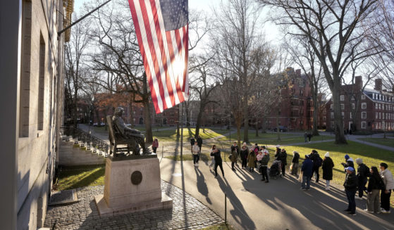 People take photos near a John Harvard statue, left, on the Harvard University campus in Cambridge, Massachusetts, on Jan. 2.