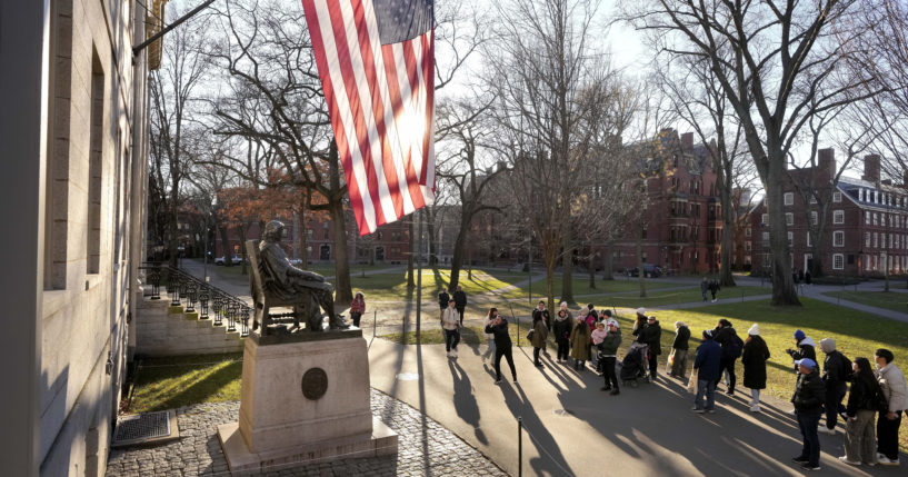 People take photos near a John Harvard statue, left, on the Harvard University campus in Cambridge, Massachusetts, on Jan. 2.