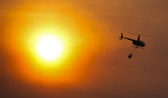 A helicopter carries a water bucket as it flies over homes burned by the Smokehouse Creek Fire Feb. 28 in Canadian, Texas.